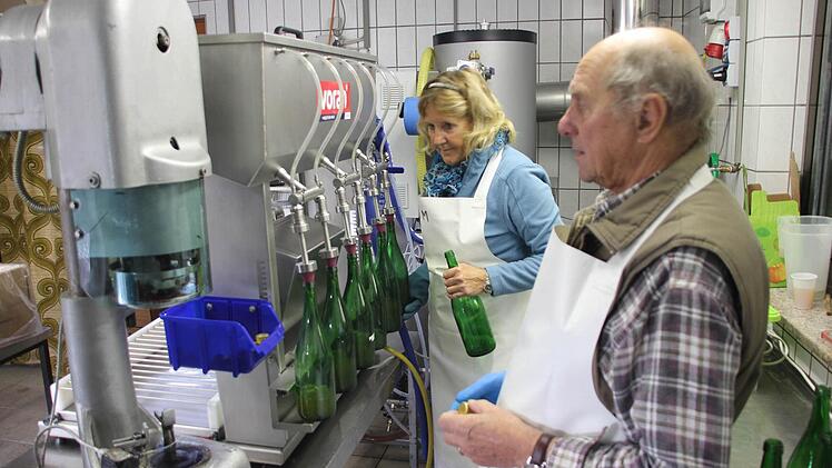 Ursula Meinhardt und Hermann Schneider an der neuen Abfüllmaschine. Die Verschlussmaschine (vorne links) befestigt die neuen Schraubverschlüsse auf den Flaschen. Fotos: Schedel
