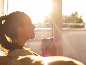 Kaffeeduft Kaffee Aroma Duft Morgen Wohnzimmer Frau Genuss Hei&szlig;getr&auml;nk Tasse Dampf Zuhause Gem&uuml;tlichkeit Sonnenlicht Fenster Sofa Entspannung Fr&uuml;hst&uuml;ck Ritual Alltag Wohlgef&uuml;hl Hygge W&auml;rme Morgenroutine Latte Becher Home Innenraum Aromatisch Kaffeepause sitting on sofa and enjoying first morning coffee on sunshine