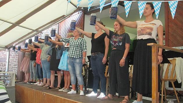 Zehn Damen ma&szlig;en ihr Durchhalteverm&ouml;gen beim Ma&szlig;krug-Stemmen im Rahmen des Elfersh&auml;user Marktfestes.  Winfried Ehling