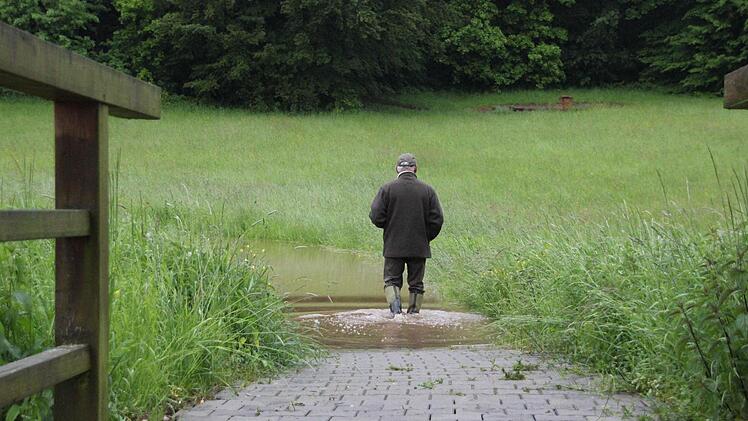 Peter Schaaf watet durch den überfluteten Radweg