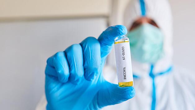 Forscher in Schutzkleidung testen den Corona-Wirkstoff.