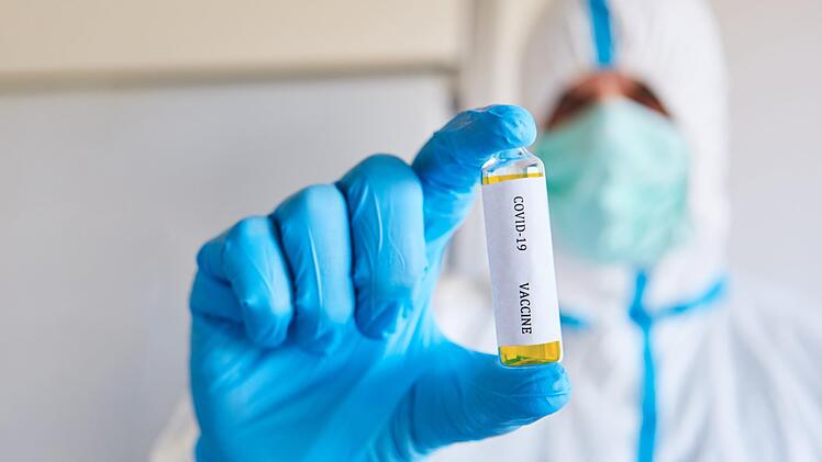 Forscher in Schutzkleidung testen den Corona-Wirkstoff.