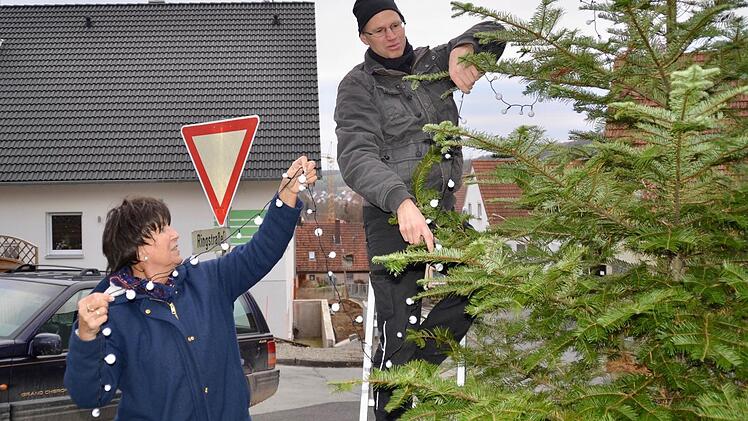 Silvia Metz und Frank Schlereth bringen eine neue Lichterkette an der jungen Tanne an.  Foto: Kathrin Kupka-Hahn