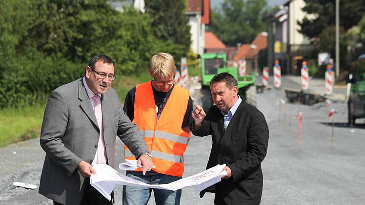 Siegfried Beck vom Bauamt, Jörg Döhler von der Baufirma Rädlinger und Bürgermeister Norbert Gräbner (von links) an der Baustelle bei Seibelsdorf. Im Hintergrund wird am neuen Gehweg gearbeitet.