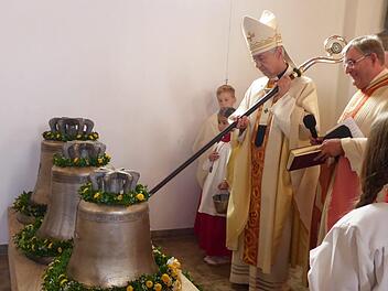 Erzbischof Ludwig Schick schlägt mit dem Bischofsstab erstmals die Glocken an - daneben Pfarrer Werner Wolf. Foto: Heidi Amon