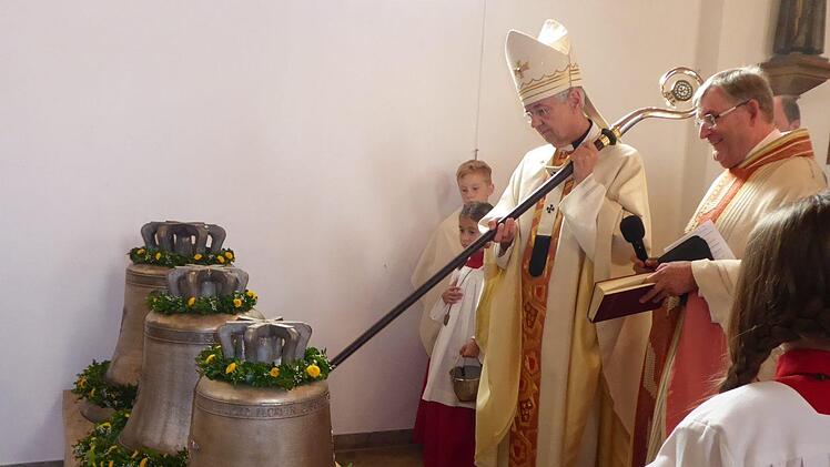 Erzbischof Ludwig Schick schlägt mit dem Bischofsstab erstmals die Glocken an - daneben Pfarrer Werner Wolf. Foto: Heidi Amon