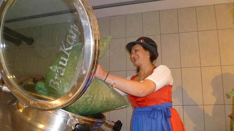 Die Bierkönigin gibt den getrockneten Hopfen in den Sud. Foto: Corinna Igler