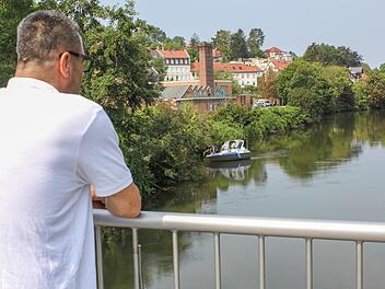 Ramadan Omeirat blickt vom Heinrich-Bosch-Steg auf die Regnitz: Im Hintergrund legt gerade ein Suchboot der Polizei an.  Foto: Sebastian Martin