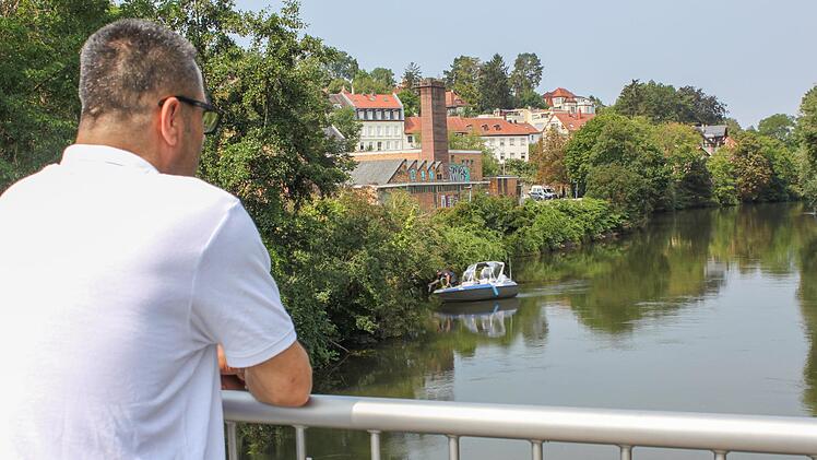 Ramadan Omeirat blickt vom Heinrich-Bosch-Steg auf die Regnitz: Im Hintergrund legt gerade ein Suchboot der Polizei an.  Foto: Sebastian Martin