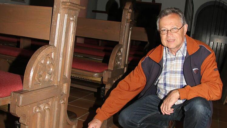 Kirchenpfleger Franz Frosch zeigt auf die kleinen Staubhäufchen bei der Kirchenbank: Sie sind der Beweis, dass Holzwürmer äußerst aktiv sind
