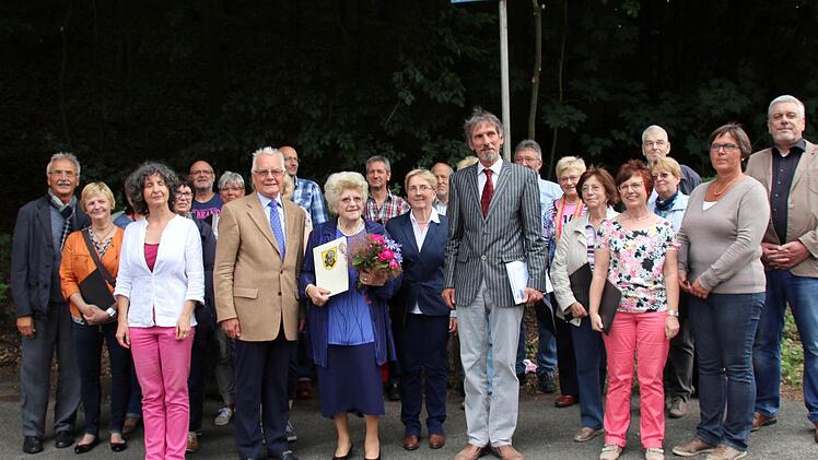 Mit der Benennung eines Weges im Pfarrschrot ehrte die Gemeinde Niederfüllbach am Samstag ihren verstorbenen Ehrenbürger Franz Möckl. Selten habe eine Ehrung so gut gepasst, meinte Bürgermeister Martin Rauscher (Bildmitte vorn), in Anwesenheit von Möckls Witwe Margit (mit Blumenstrauß), des Vorsitzenden des Fränkischen Sängerbundes Peter Jacobi (vorn, 2. von links) und Norbert Tessmer als Vorsitzender der Niederfüllbacher Stiftung (rechts). Die Einweihung wurde untermalt von Liedern des Kompo...