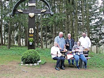 Elisabeth und Thomas Schütz, Ludwig Melzer, Claudia Schütz mit Töchterchen Victoria sowie Alexander Schütz (im Bild, von links) machen Brotzeit auf der neuen Sitzbank vor dem Wegekreuz.