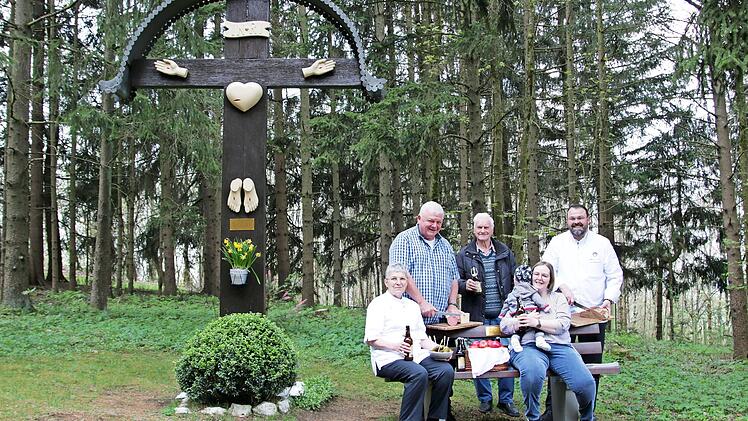 Elisabeth und Thomas Schütz, Ludwig Melzer, Claudia Schütz mit Töchterchen Victoria sowie Alexander Schütz (im Bild, von links) machen Brotzeit auf der neuen Sitzbank vor dem Wegekreuz.