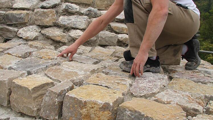 Thomas Korsch von der Firma Preuße & Rätsch legt Hand an die obere Deckschicht aus neuen Muschelkalksteinen.