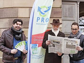 Werbegemeinschaftsvorsitzender Heiko Grom (links) mit der Gutschein-Mappe, an der sich auch die Saale-Zeitung beteiligt, wie OB Kay Blankenburg und der stellvertretende Vorsitzende von Pro Bad Kissingen, Michael Pal, beweisen. Foto: Thomas Mäuser