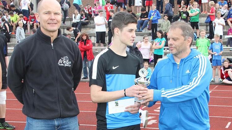 Initiator und Rekordhalter Ralf Marlok (11,2 Sekunden) überreicht Nikolai Masel den Pokal. Der Neuntklässler darf einen Monat mit Betreuung im Sportstudio Fit'n'fun von Stefan Schmidt (links) trainieren.