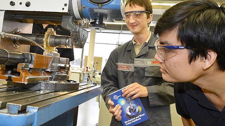 Man Nguyen (rechts) betrachtet im Bosch-Ausbildungszentrum Bamberg eine Fräsmaschine.  Künftig soll er in seiner Heimat Vietnam als Bosch-Ausbildungsmeister junge Menschen betreuen.  Vorbild ist dabei der Bamberger Ausbildungsmeister Mario Fischer (links). Foto: R.  Rinklef