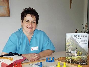 Ute Engelhardt-Gleich zeigt eine Auswahl Hilfsmittel, die bei der Betreuungstätigkeit zum Einsatz kommen. Seien es Brettspiele, Bücher zum Vorlesen, das Gebetbuch oder auch nur ein Kuschelkissen, das alles hilft, auch zu Bewohnern vorzudringen, die bereits unter fortgeschrittener Demenz leiden. Foto: Susanne Deuerling