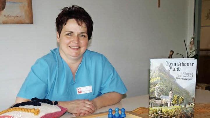 Ute Engelhardt-Gleich zeigt eine Auswahl Hilfsmittel, die bei der Betreuungstätigkeit zum Einsatz kommen. Seien es Brettspiele, Bücher zum Vorlesen, das Gebetbuch oder auch nur ein Kuschelkissen, das alles hilft, auch zu Bewohnern vorzudringen, die bereits unter fortgeschrittener Demenz leiden. Foto: Susanne Deuerling