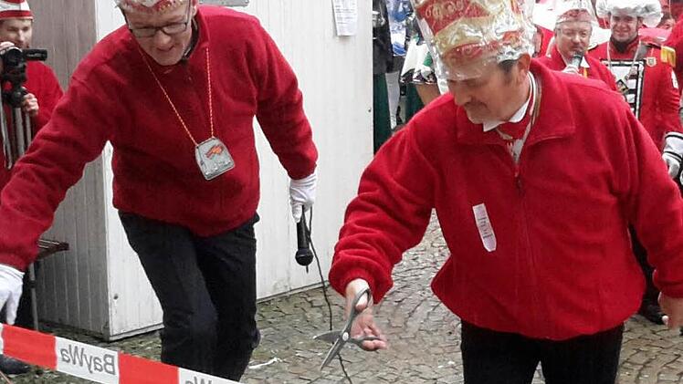 Vor dem Weg ins Rathaus mussten von den Karnevalisten erst etliche Barrikaden beseitigt werden. Den Startschuss dazu gaben Frank Vogler (links) und Peter Pankerl (rechts) mit dem Durchschneiden der Absperrung. Foto: Rolf Pralle