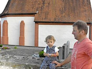 Die zweijährige Lenia war die jüngste Teilnehmerin bei der Ortsbegehung in Birkach. Ihr Papa, Manfred Schirdewahn (rechts), war damit als Gemeinderat, Bauhofleiter der Gemeinde Burgpreppach und Kindermädchen gleich in dreifacher Funktion gefordert. Im Hintergrund die Friedhofskapelle.  Foto: Gerhard Schmidt