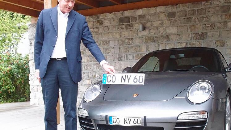 Am Porsche befindet sich das Klebekennzeichen, Michael Stoschek hält das Original-Kennzeichen in der Hand: Im August, kurz nachdem er den Strafbefehl erhalten hatte, demonstrierte der Unternehmer den Vergleich. Foto: CT-Archiv/Jochen Berger