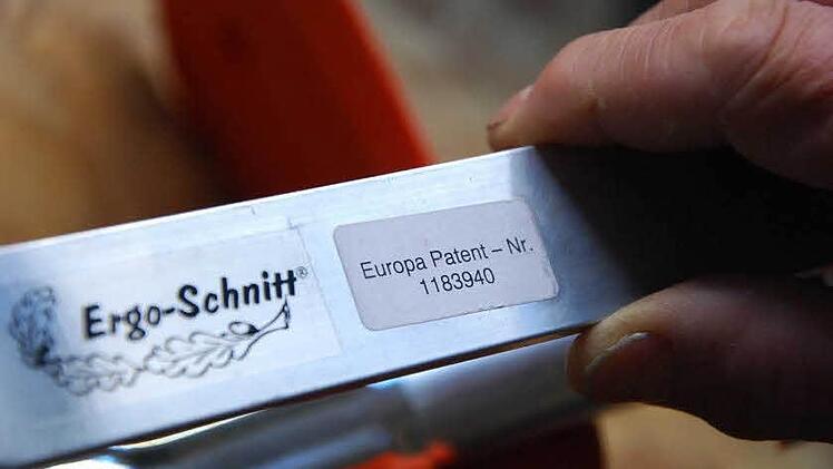 Paul Schmitt mit seiner erfolgreichsten Erfindung - dem "Sicherheitsgrasschneideblatt". Der passende, "klappbare Kanten- und Rindenschutz" sorgt dafür, dass die Motorsense auch den Baum nicht verletzt. Der 73-jährige Tüftler hat schon einiges beim Patentamt angemeldet. Zuletzt seine neueste Erfindung: der "Kunststoffflaschenhalter". Foto: Carmen Schmitt
