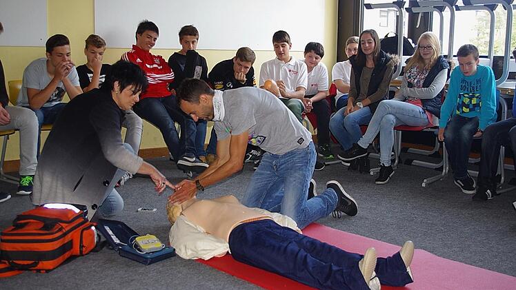Claudia Simon zeigt Felix Mayerhöfer, Lehrer der Klasse 8 b, wie eine Mund-zu-Mund-Beatmung funktioniert. Foto: Schülein