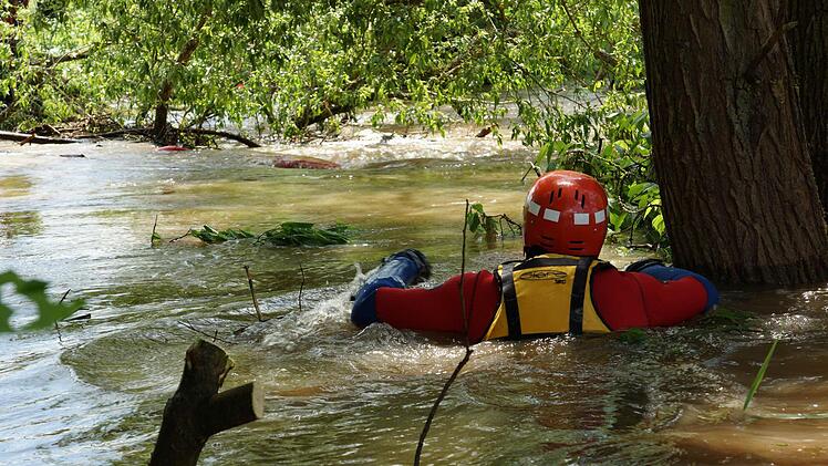 Ein Wasserwachtler versucht ans gekenterte Boot zu kommen.