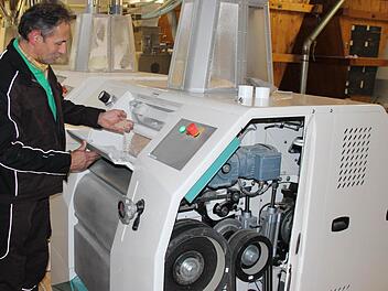 Siegfried Ebert kontrolliert den Mahlvorgang des Getreides. Normalerweise sind alle beweglichen Teile abgedeckt. Für das Foto hat Ebert ausnahmsweise die Abdeckung geöffnet und einen Einblick in die Technik gegeben.  Foto: Friedwald Schedel