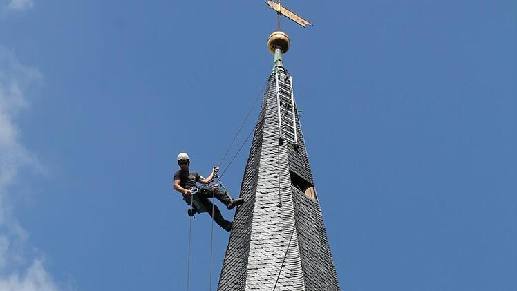 Ein Mitarbeiter des "Team Alpin" inspiziert in schwindelerregender Höhe die Schieferziegeln an der Außenwand des Kirchturms. Foto: Christian Dreßel