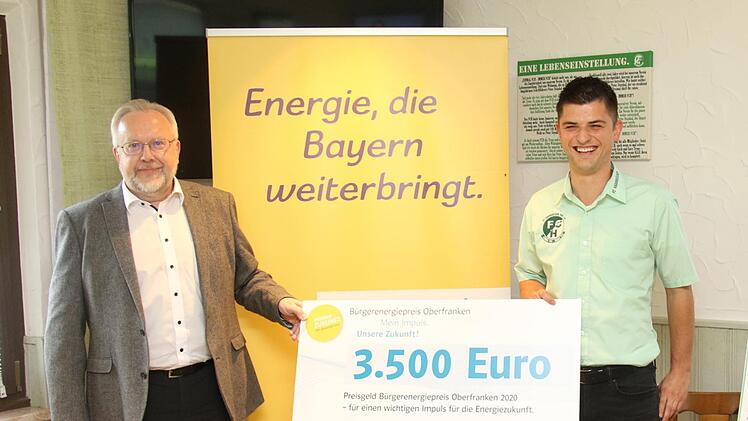 Karl Krapf vom Bayernwerk  (links) überreicht an den Vorsitzenden des FC Haarbrücken, Simon Weber (Mitte), den Bürgerenergiepreis in Höhe von 3500 Euro. Foto: Michael Stelzner