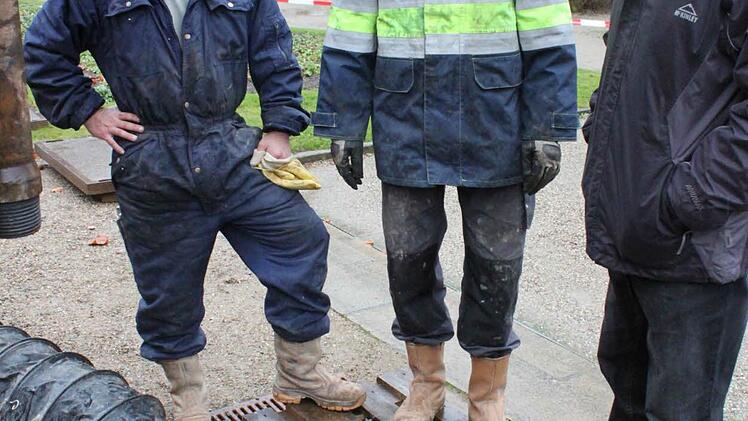 Richard Schmitt, Dirk Wolff und ein Mitarbeiter der Bohrfirma blicken auf das zurück laufende Wasser in der Brunnenstube.