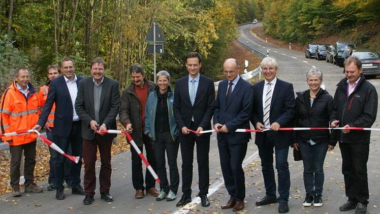 In weniger als zwölf Monaten konnte der zeitlich vorgezogene Ausbau der Kreisstraße HAS 26 von Fabrikschleichach nach Hundelshausen  abgeschlossen werden. Die beiden Landräte Wilhelm Schneider und Florian Töpper (Vierter und Fünfter von rechts) schnitten gemeinsam mit Bürgermeister Matthias Bäuerlein (Dritter von links), Manfred Rott (Dritter von rechts) vom Staatlichen Bauamt, dem Leiter des Kreis-Tiefbaus Alfons Schanz (Vierter von links), den Vertretern der Baufirma, des Planungsbüros und ...
