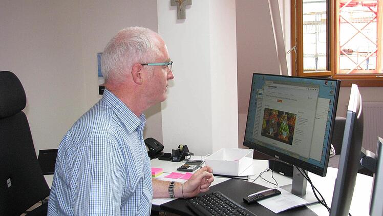 Johannes Simon, Leiter von Pfarrbriefservice.de und gleichzeitig Vorsitzender des Kreiscaritasverbandes, an seinem Schreibtisch im neuen Büro.
