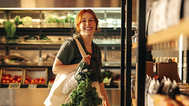 Happy young woman grocery shopping in a supermarket