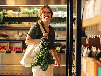 Happy young woman grocery shopping in a supermarket