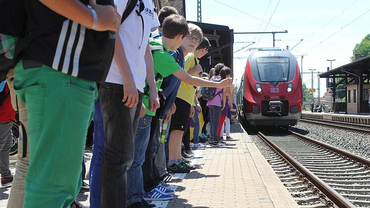 Schüler stehen in Kronach dicht am Gleisbett während der Zug einfährt. Foto: Jan Koch