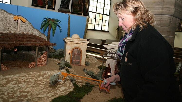 Annette Walter arbeitet mit einer Zange, um auch die hintersten Winkel der großen Krippe zu erreichen.
