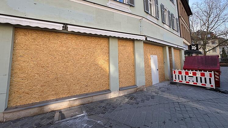 In der Bamberger Innenstadt sind Schaufenster eines Geb&auml;udes mit Holzplatten verkleidet. Bald zieht dort eine bekannte Kette ein. Neben der Baustelle steht ein roter Container.