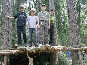 Einige der mutigen "Waldkinder" präsentieren stolz ihre urige Hütte, die sie während der Aktionswoche im Wald bei Wüstenahorn gebaut haben.
