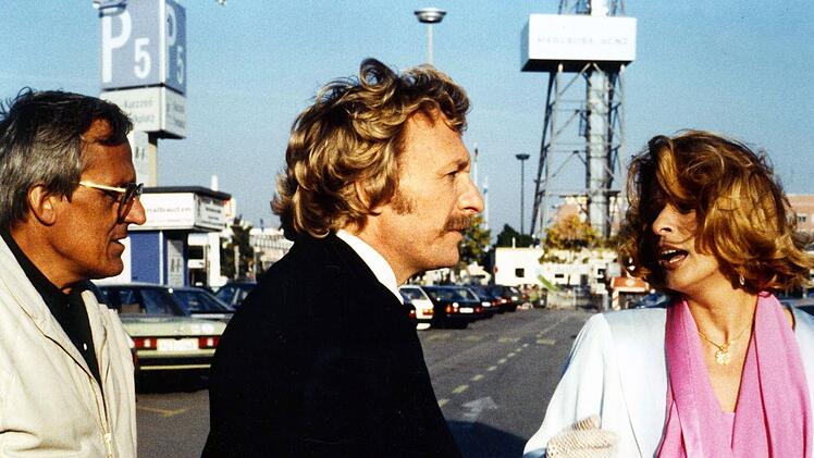 Herbie (Dieter Hildebandt, links) und Baby (Franz Xaver Kroetz) holen Babys Freundin Mona (Senta Berger) vom Flughafen ab. Leider stehen die beiden so unter Stress, dass der Empfang gr&uuml;ndlich daneben geht.