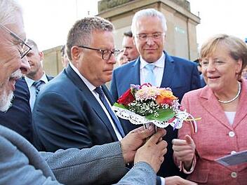 Bad Bocklets Altbürgermeister Wolfgang Back überreicht der Kanzlerin ein Biedermeiersträußchen. Foto: Heike Beudert