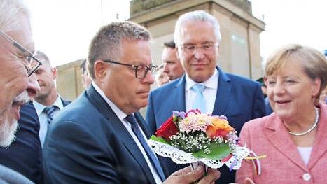 Bad Bocklets Altbürgermeister Wolfgang Back überreicht der Kanzlerin ein Biedermeiersträußchen. Foto: Heike Beudert