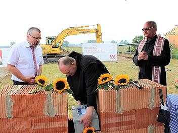 Provinzial Benedikt Hau versenkt die Kiste mit den Zeitdokumenten symbolisch in der Mauer. Geschäftsführer Günther Allinger (links) und Dekan Kilian Kemmer schauen zu.    Foto: Evi Seeger