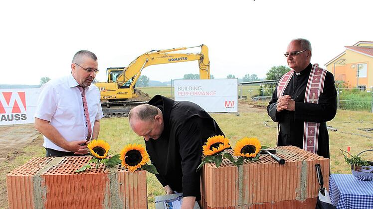 Provinzial Benedikt Hau versenkt die Kiste mit den Zeitdokumenten symbolisch in der Mauer. Geschäftsführer Günther Allinger (links) und Dekan Kilian Kemmer schauen zu.    Foto: Evi Seeger