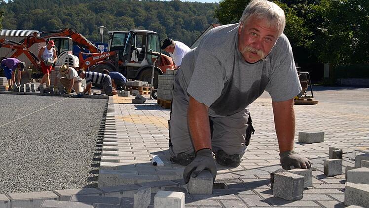 Puzzlearbeit: Norbert Wegemer ist hier dabei, Pflastersteine entlang der kurvigen Zufahrt zu verlegen. Seine Mitstreiter im Hintergrund hingegen haben es etwas einfacher. Sie können das Pflaster einfach so, ohne große Hindernisse verlegen. Foto: Kathrin Kupka-Hahn