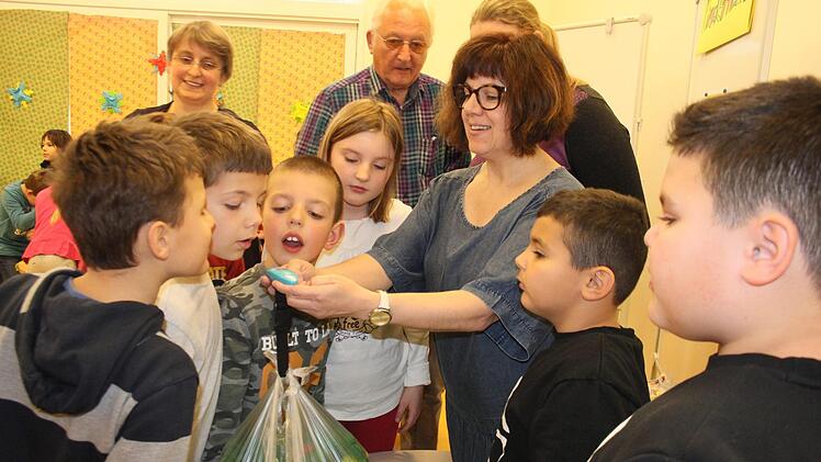Tina Lauer wiegt das Säckchen mit den Plastikdeckeln ab und lässt die Kinder das Gewicht raten. Im Hintergrund verfolgen Helene Sabelfeld und Hendrik Seegebarth die Aktion.  Fotos: Bernhard Panzer