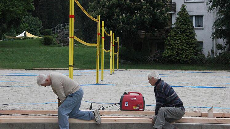 Gerhard (links) und Georg Grebner befestigen die Kanthölzer rund um die Beachvolleyballfelder.  Foto: Friedwald Schedel