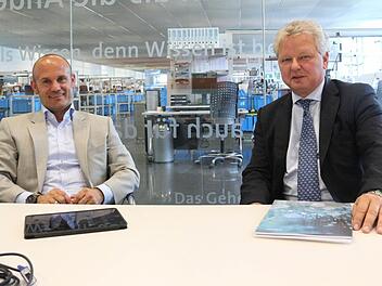 Björn Schumacher und Frank Wöhner im Besprechungszimmer mit Durchblick in die Fertigung bei Wöhner. Beide Unternehmer sind überzeugt davon, dass ihre Unternehmen sich nur dann weiterentwickeln können, wenn es möglich ist, von Coburg aus zu den übrigen Standorten zu fliegen.Foto: Simone Bastian